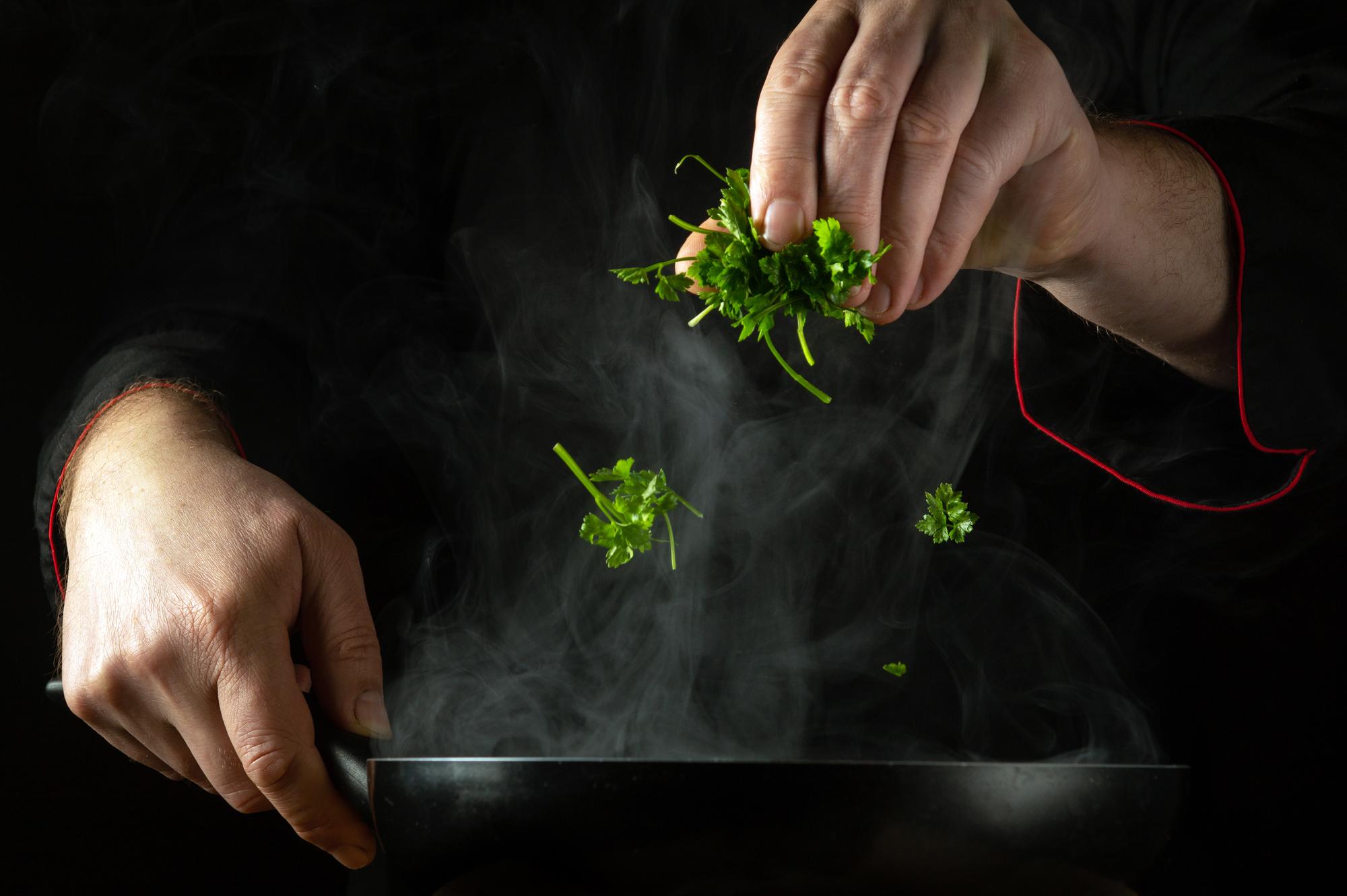 Founder hands sprinkling herbs over dish